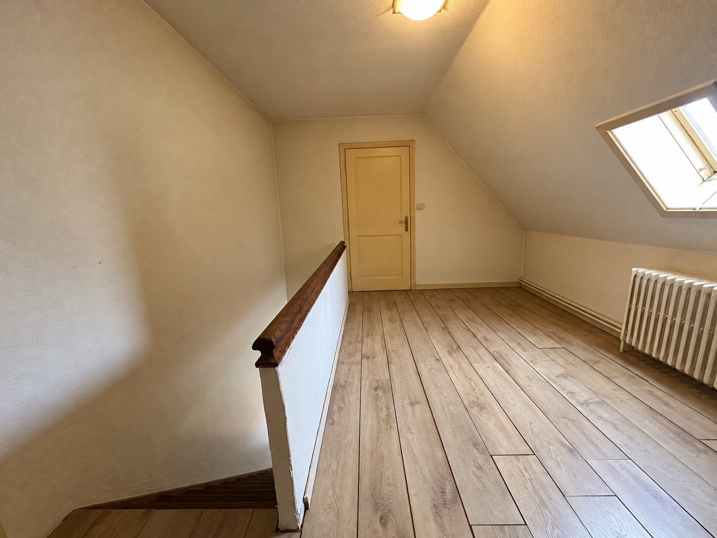 De lege overloop met dakraam en houten leuning