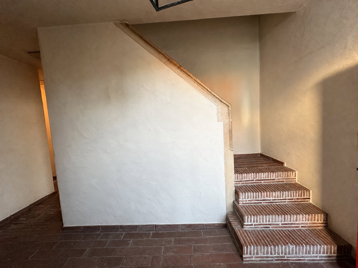 De lege inkom met bakstenen trap en een lichte muur
